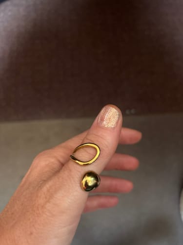 Customer's gold-toned Aurora Ring worn on a finger, showing its sleek, wave-like open design.