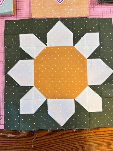 Reviewer's finished flower quilt block from the Spring Fling Sew-Ready Quilt Kit, showing a large yellow center.