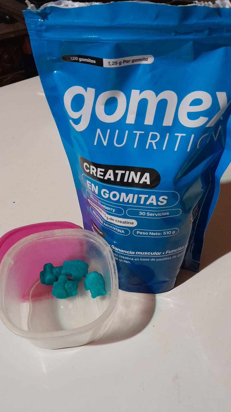 Customer's Gomitas de Creatina GOMEX packaging and a small container with a few teal gummy supplements on a white surface.