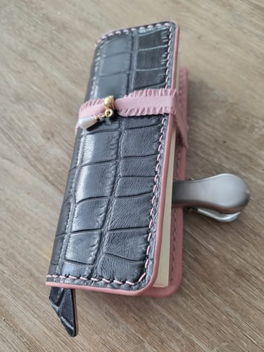 Customer's Index Notebook 3.0 in black crocodile-textured material with pink trim, closed with a small charm