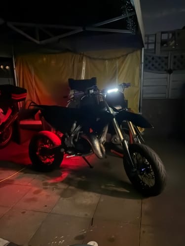 Customer's Universal Supermoto/Dirtbike tail tidy installed on a dark motorcycle, illuminated in a dimly lit garage.