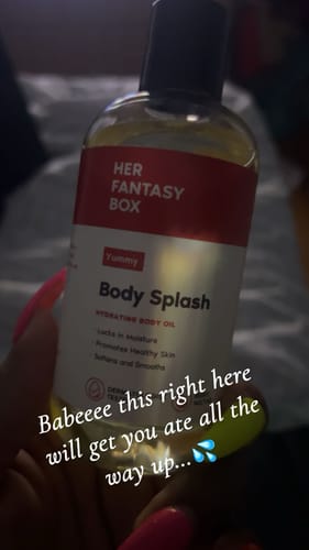 Reviewer holding the clear bottle of Yummy Body Splash against a blurred background.