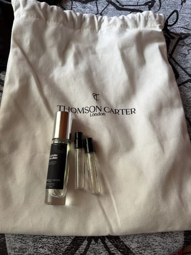 Customer's Redroom Eau de Parfum bottle and two small sample vials placed on a white cloth storage bag.