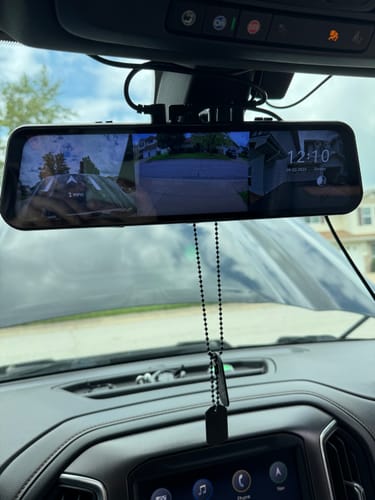 Customer's digital dash cam mirror installed in a vehicle, displaying camera feeds on the screen.