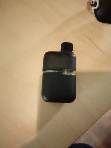 Customer's compact black THCA vape device sitting on a light wooden surface.