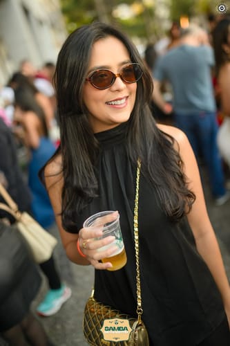 Customer's Óculos de Sol Barra com lentes escuras em uso por pessoa em ambiente externo e festivo.