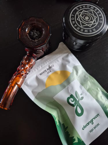 Customer's White Runtz product packaging, glass pipe, and a black grinder on a dark surface.