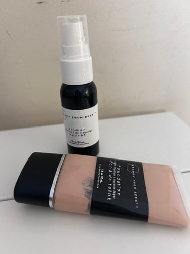 Customer's Foundation bottle resting next to a Beauty From Bees primer bottle on a white surface.