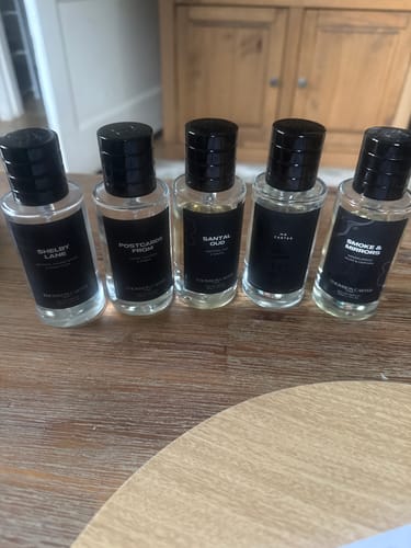 Customer's Mr Carter perfume collection featuring five small clear glass fragrance bottles on a wooden table.