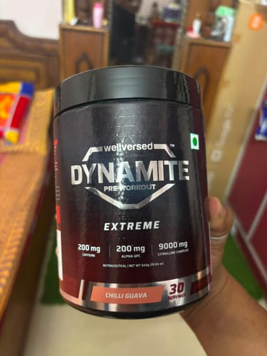 Customer's hand holding a tub of Dynamite Pre-Workout EXTREME in Chilli Guava flavor.