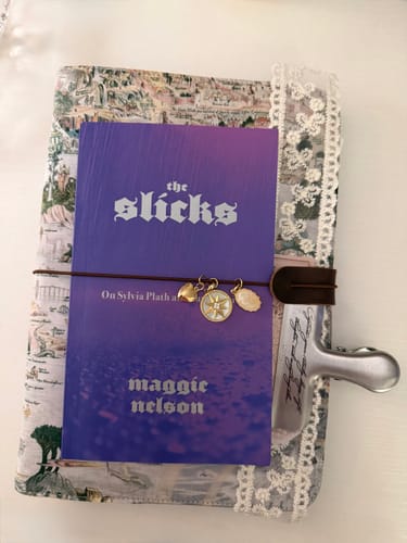 Customer's floral Liberty Cotton binder with decorative charms and a metal clip resting on top.