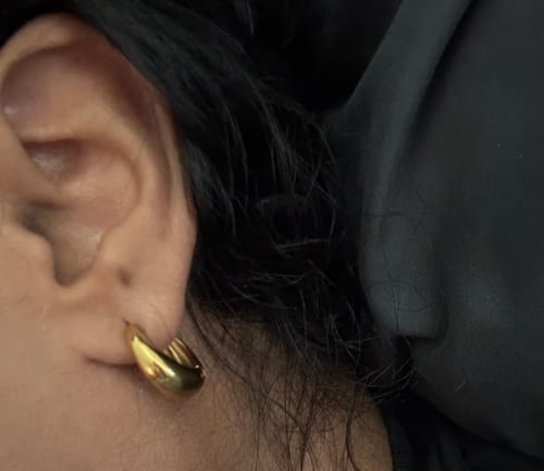 Customer's Mini Drop Huggies gold hoop earring worn on an earlobe.