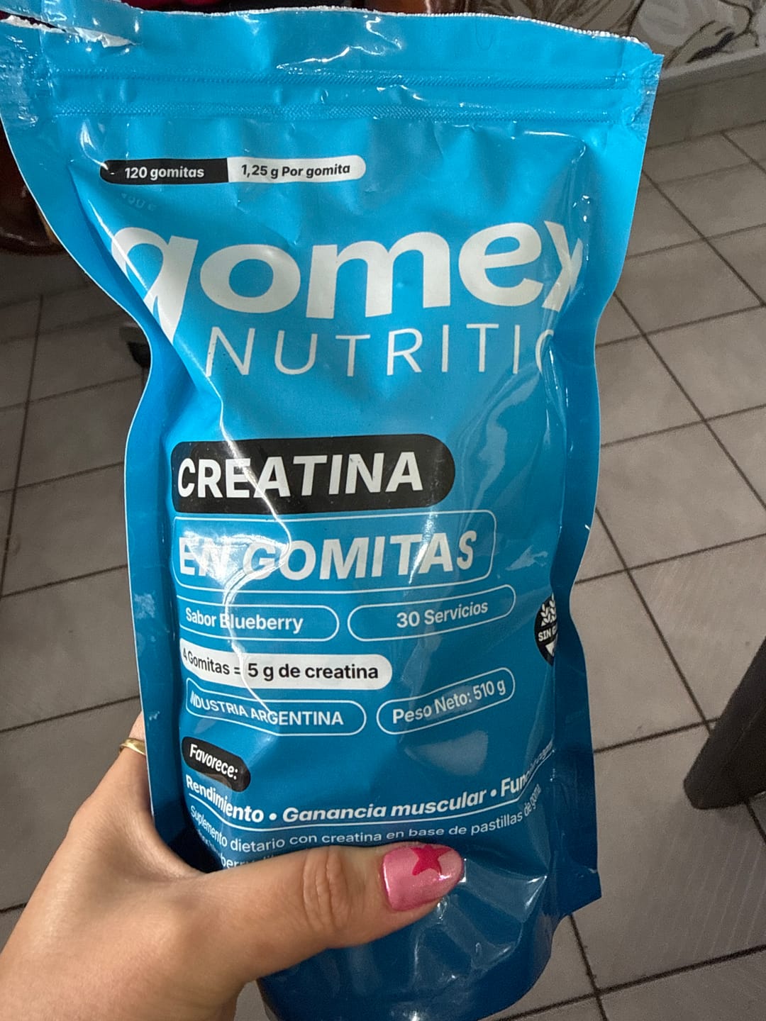 Customer's hand holding a blue bag of Gomex Creatina gummies.