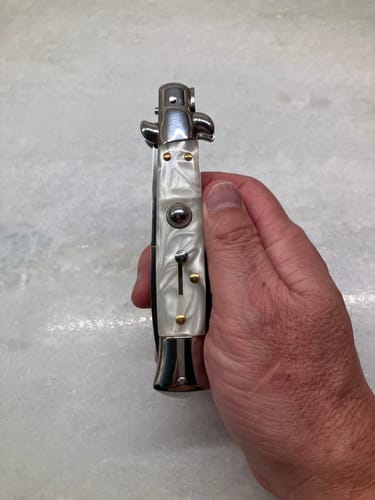 Customer's Italian Style Switchblade with a marbled handle held in a hand while closed.