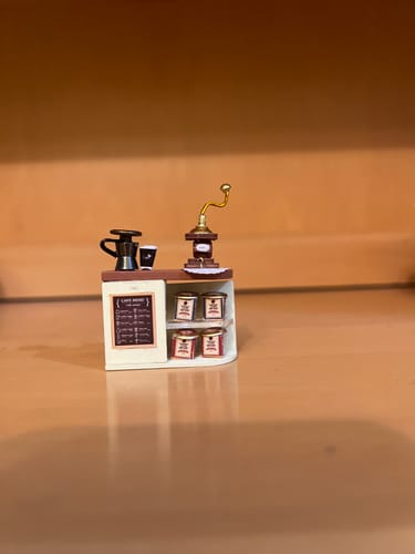 Customer's Daily Grind miniature coffee bar unit featuring a brass hand grinder, coffee pots, and shelving.