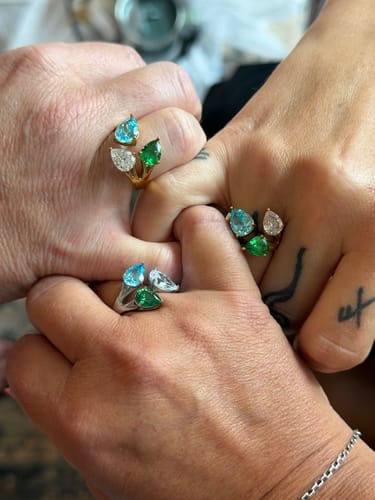 Customer's three hands joined together, each wearing a gold-plated Aurora Birthstone Ring with pear-shaped stones.
