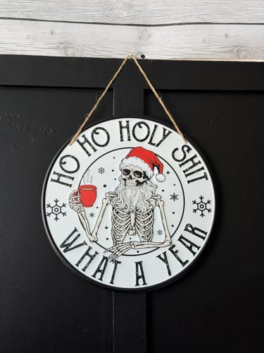 Customer's What A Year round metal sign showing a skeleton with a Santa hat holding a red mug.