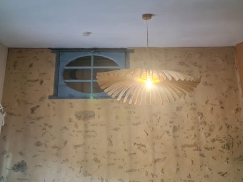 Customer's Cygne teinté chêne suspension accrochée au plafond devant un mur en pierre rustique