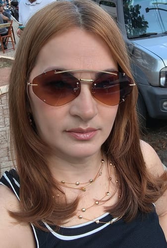 Reviewer vestindo o Óculos de Sol Diamond com lentes avermelhadas, mostrando o design sem aro e moderno.
