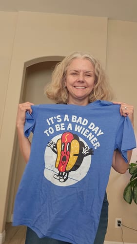 Reviewer holding up the blue It's a Bad Day To Be a Wiener T-shirt featuring a cartoon hot dog graphic.