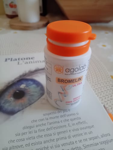 Customer's Bromelin Ultra supplement bottle with an orange cap resting on a book.