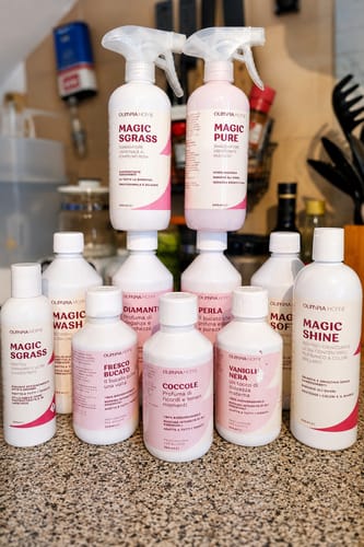 Customer's Perla laundry detergent among various Olimpia Home bottles arranged on a kitchen counter.