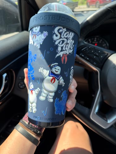 Customer's hand holding a dark blue Ghostbusters Stay Puft To-Go Buddy tumbler in a car interior.