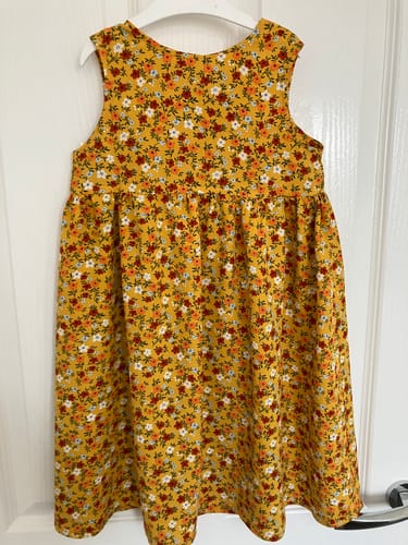 Customer's dress made from yellow floral Blossom Belle Viscose Fabric hanging on a white door.