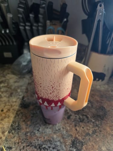 Customer's Thicc Buddy mug with spill-proof lid and handle, shown standing on a kitchen counter.