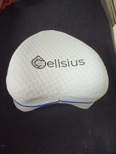 Customer's white Cellsius genoux cushion with a logo, resting on a dark surface.