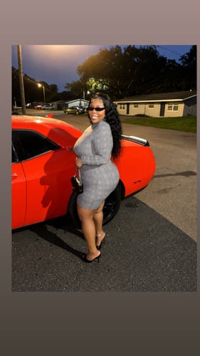 Reviewer standing next to an orange car wearing the grey printed Naked Print Mini Dress.
