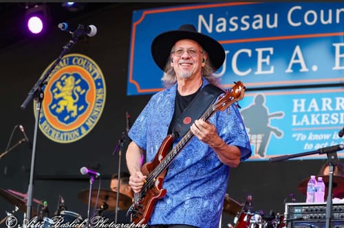 Customer's Big Wide Brim Felt Hat being worn by a musician playing bass guitar on a large outdoor stage.