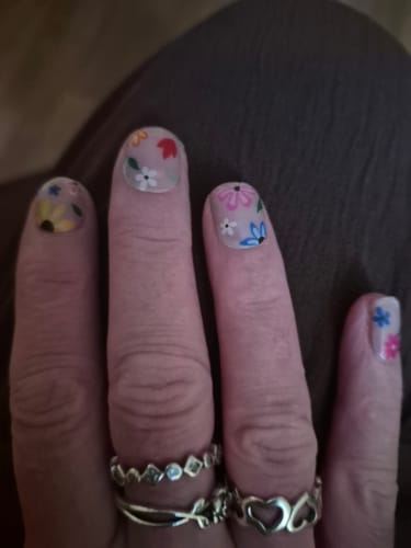 Customer's Hawaii gel nail stickers on hand, featuring colorful floral patterns on a clear base.