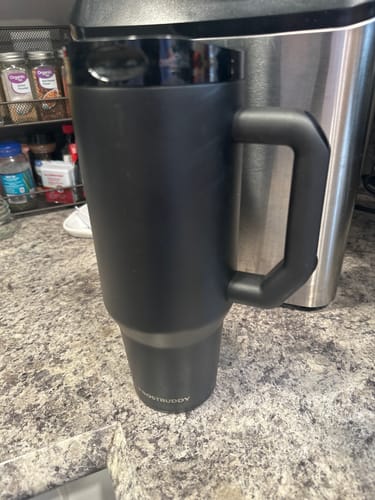 Customer's black Thicc Buddy 40oz mug sitting on a kitchen counter in front of a stainless steel appliance.