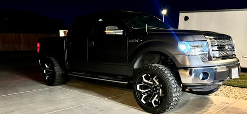 Reviewer's black Ford F150 with a 3-inch front lift kit installed, parked on a concrete driveway at night.