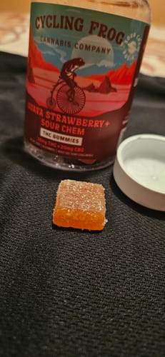 Customer's Guava Strawberry Rosin Gummies bottle next to a single orange, sugar-coated gummy.
