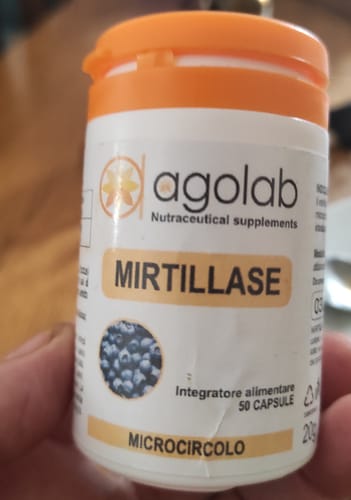 Customer's hand holding a white bottle of Mirtillase Forte, showing the label and orange cap.