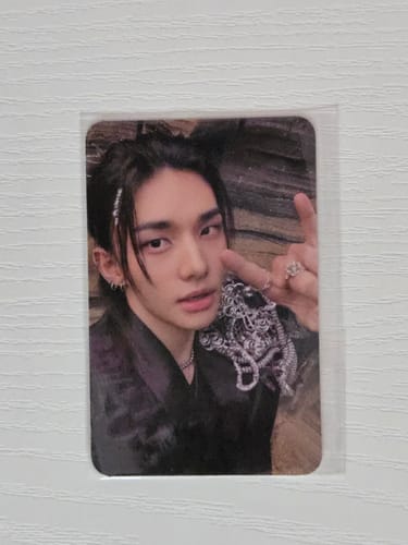 Customer's Stray Kids photocard showing a person posing with a hand gesture against a textured backdrop