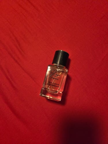 Reviewer's kleiner Taschenzerstäuber mit schwarzem Deckel auf einem roten Hintergrund.