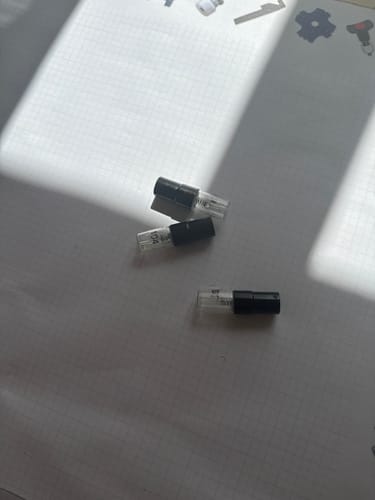 Kundenfoto des Tester-Sets mit drei kleinen Parfum-Probierfläschchen auf einer hellen Unterlage.