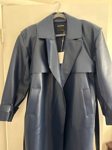 Customer's blue Vegan Leather Trench Coat hanging on a door, showing the oversized fit and collar details.
