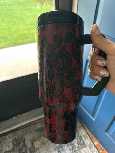 Customer's hand holding a red and black lace patterned Thicc Buddy mug.