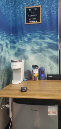 Customer's To-Go Buddy composition notebook print tumbler sitting on an office desk next to a coffee machine.