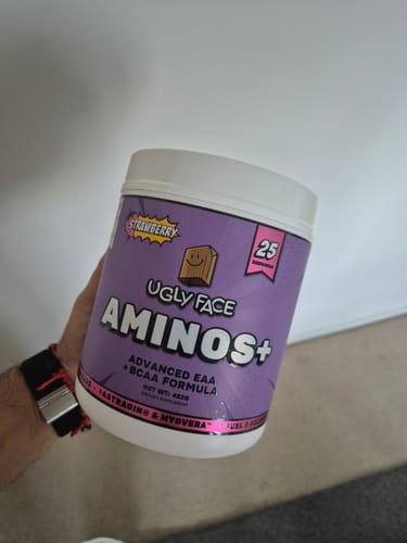 Customer's hand holding a purple Ugly Face Aminos plus tub with a white lid