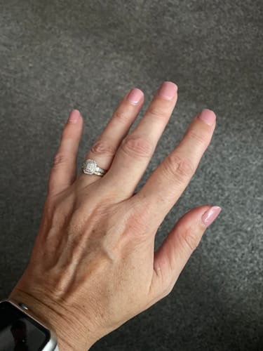 Reviewer's hand showing natural nails with a subtle, light pink First Kiss gel manicure and a diamond ring.