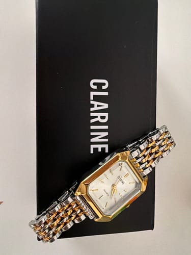Customer's CLAIRE DE MAINS watch with silver and gold-tone metal band on top of a black Clarine branded box.