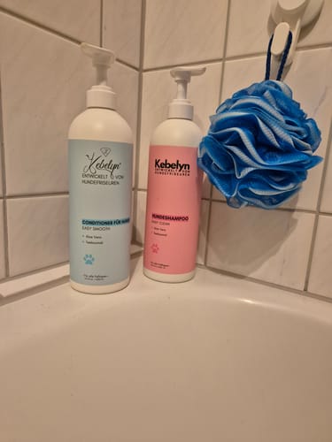Reviewer's Hundeshampoo Easy Clean bottle next to a conditioner bottle and a blue bath puff in a tiled shower.