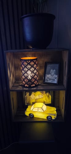 Customer's Nata LED lyslykt med palmemønster plassert i en hylle, som gir en stemningsfull belysning.