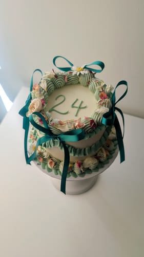 Customer's White Wedding Flowerfetti sprinkled on a decorated cake with a green ribbon and the number twenty four.