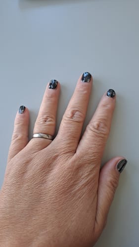 Reviewer's Hand mit aufgetragenen The Twinkling Lights Nagelfolien in Schwarz mit silbernen Lichterketten-Motiven.